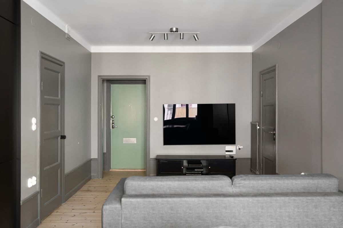 Wall-mounted flat-screen television above a media console in a gray minimalist living room